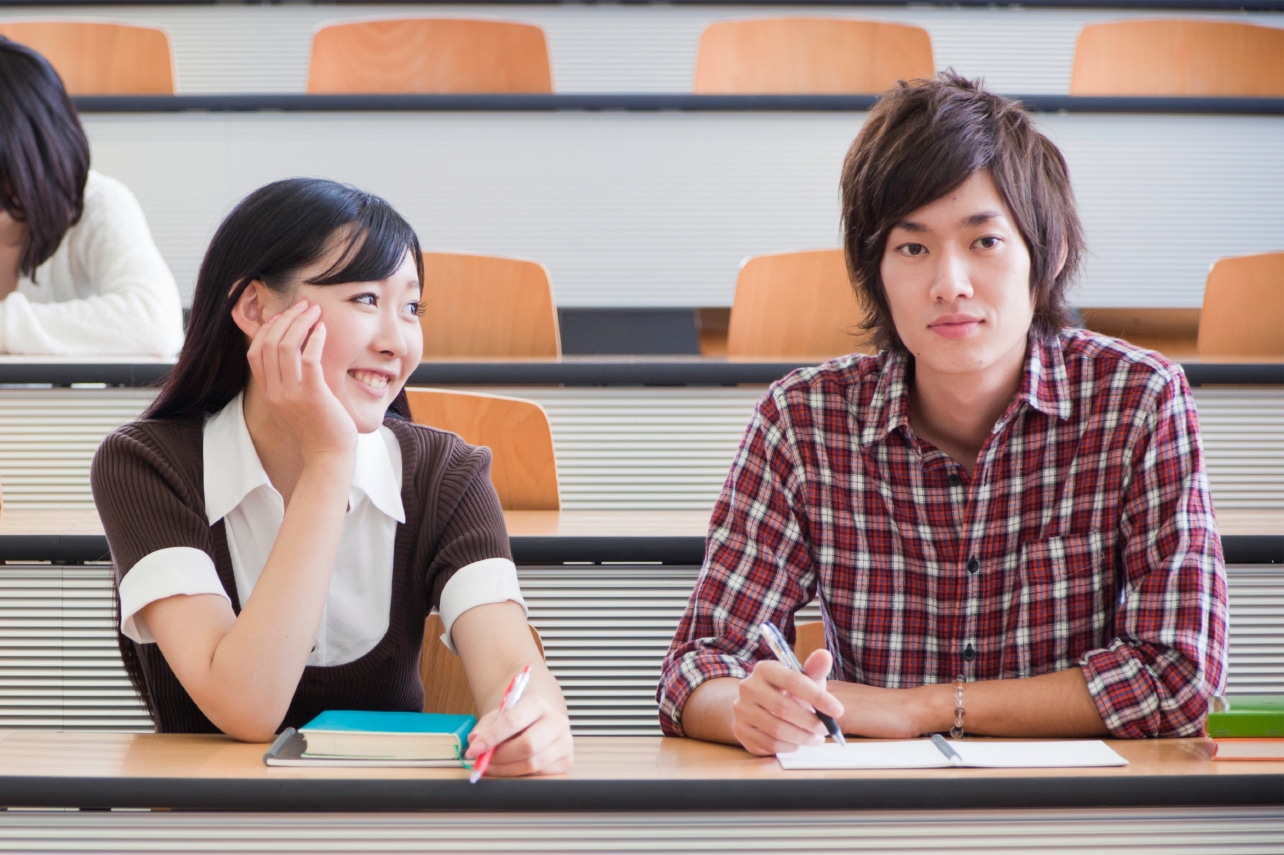Female student smiling at male student seated next to her in lecture hall