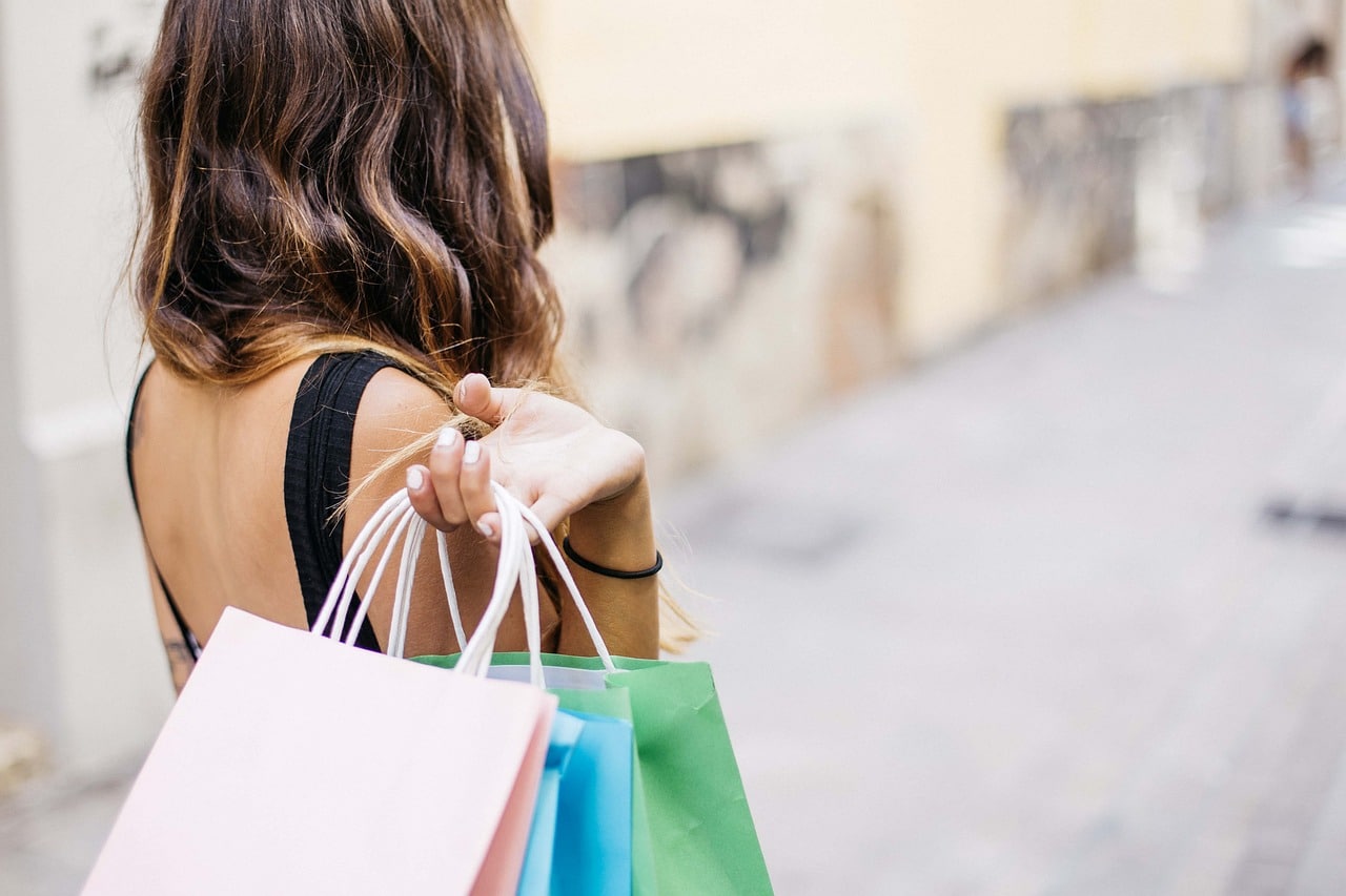 woman-holding-pink-blue-and-green-shopping-bags-on-her-shoulder-and-behind-her-back