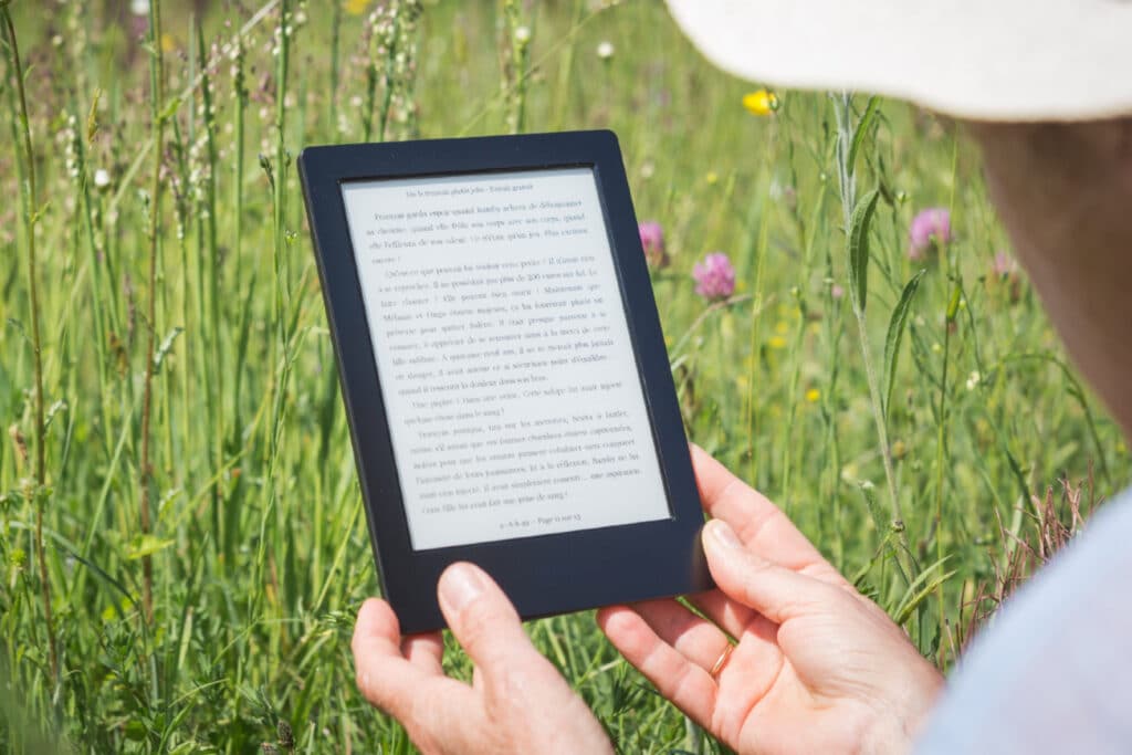 Person holding an ereader in the grass