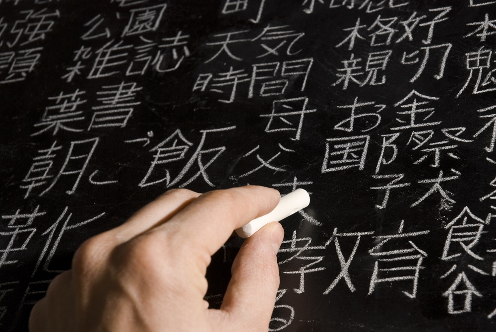 a man writing kanji on a blackboard