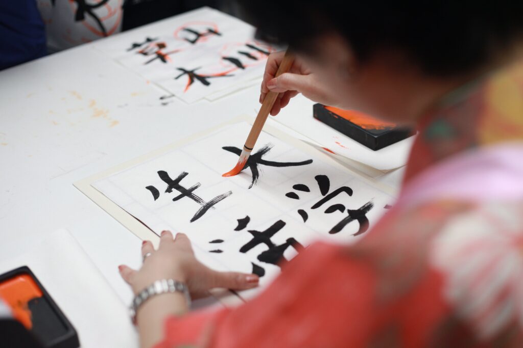 A Japanese woman paints kanji characters