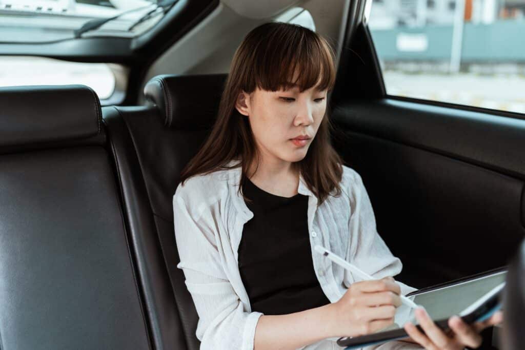 woman-of-asian-descent-working-on-tablet-while-inside-car