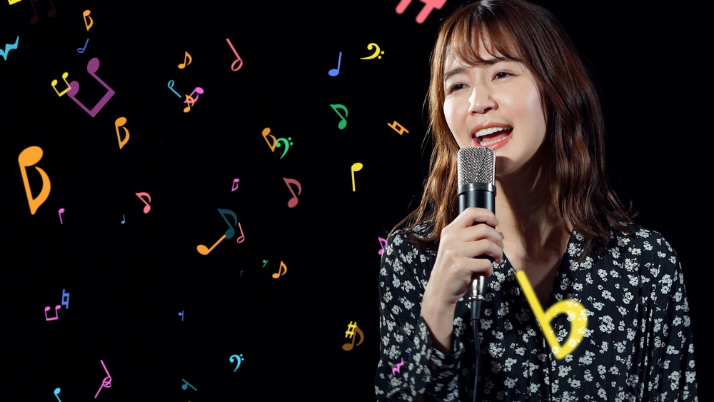 an image showing a woman singing in a microphone on a black background with the colorful notes