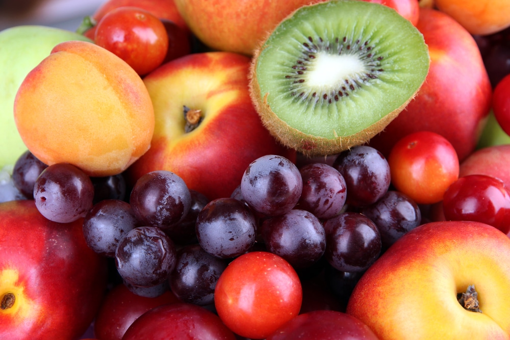 Piled fruits including kiwi grape apple apricot