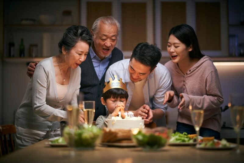 little-asian-boy-makes-a-wish-on-his-birthday-with-his-family-around