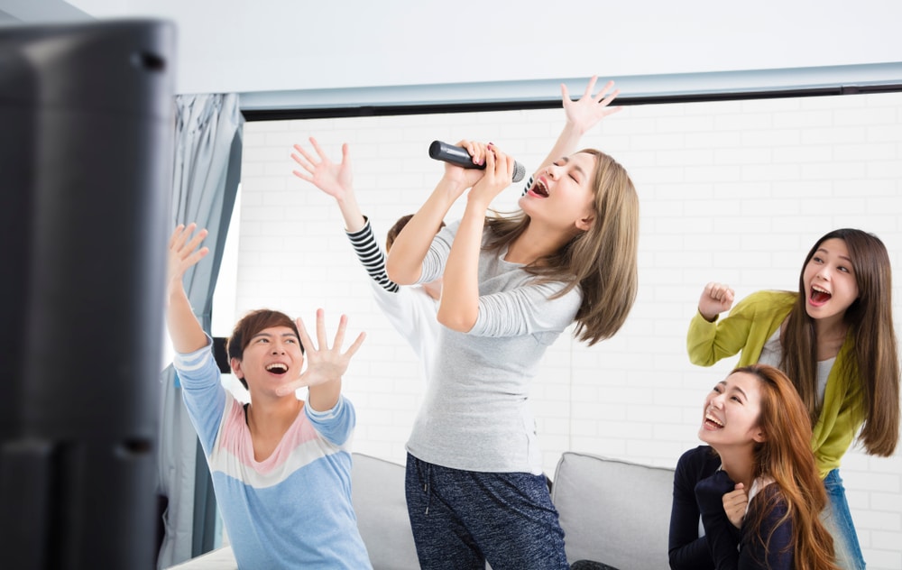 women and man singing karaoke together