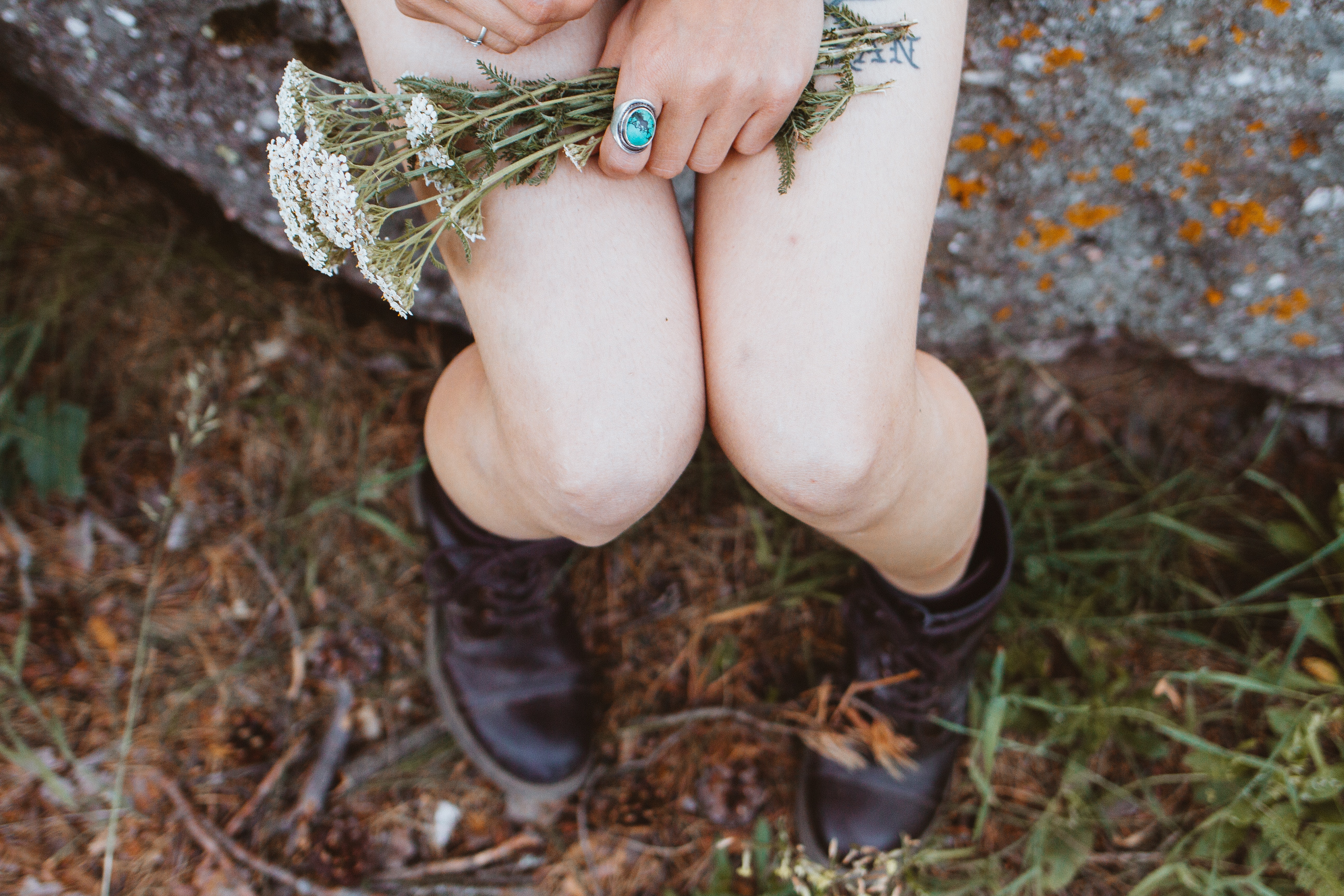 Close-up of the knees of a seated woman holding flowers