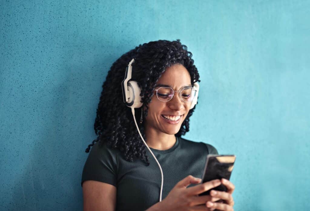 woman-smiling-and-listening-to-headphones-looking-at-her-phone