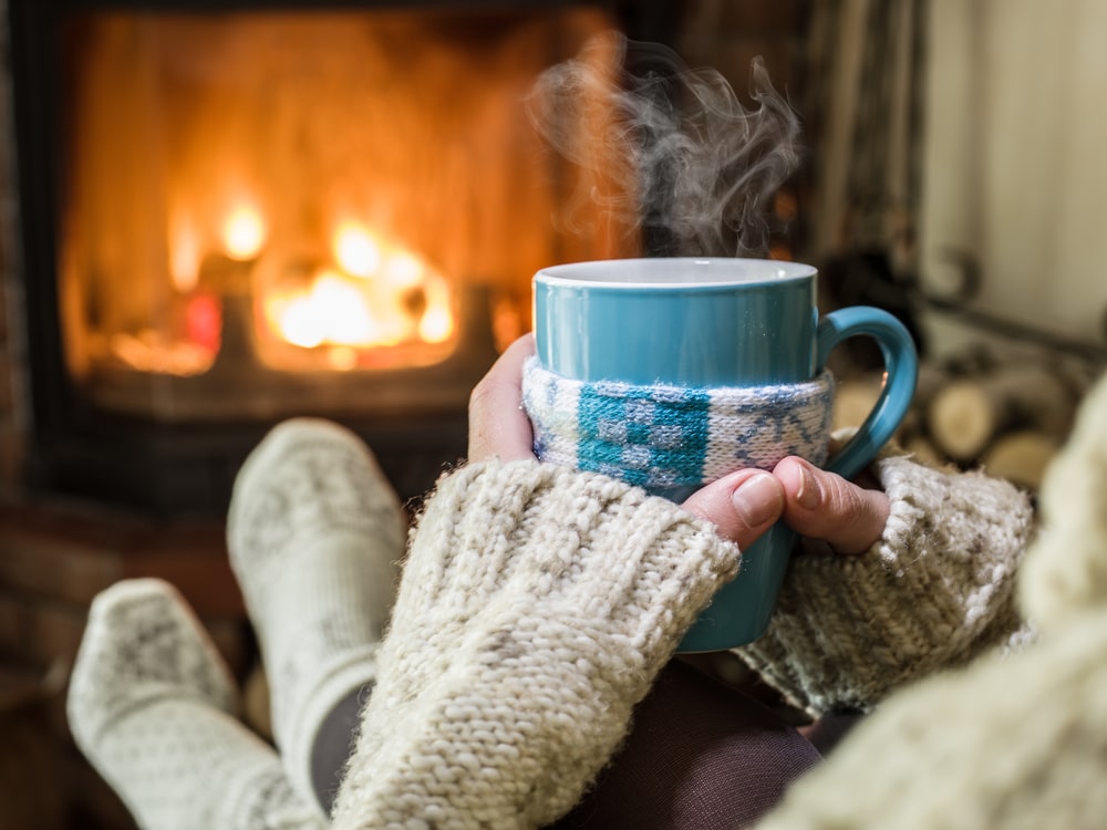 Warming and relaxing near fireplace with a cup of hot drink