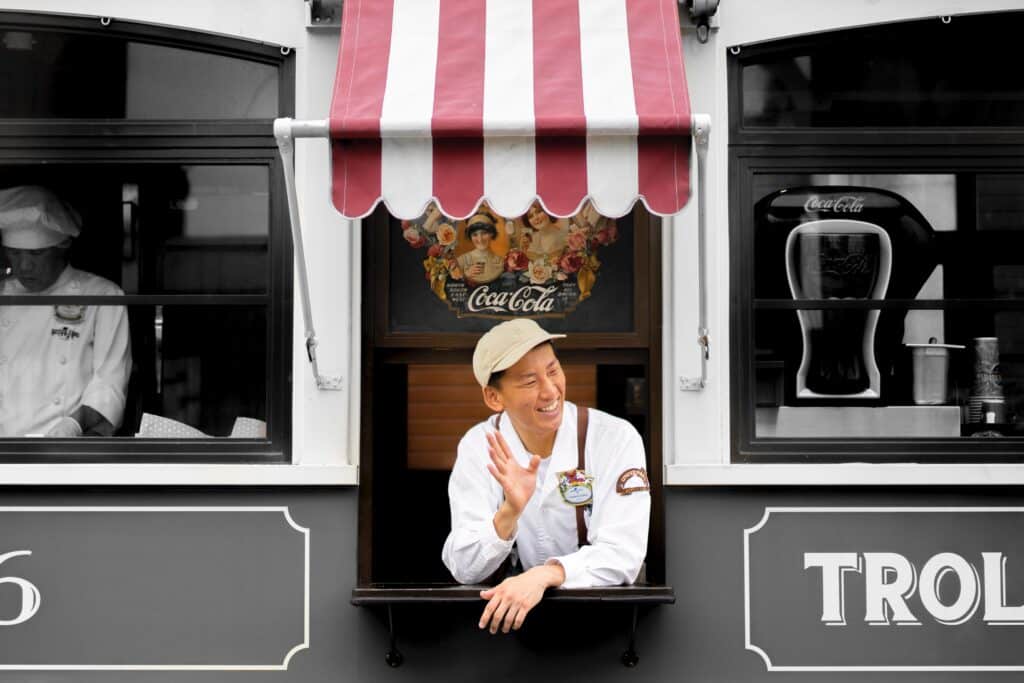 A Korean man working in a food truck waves goodbye