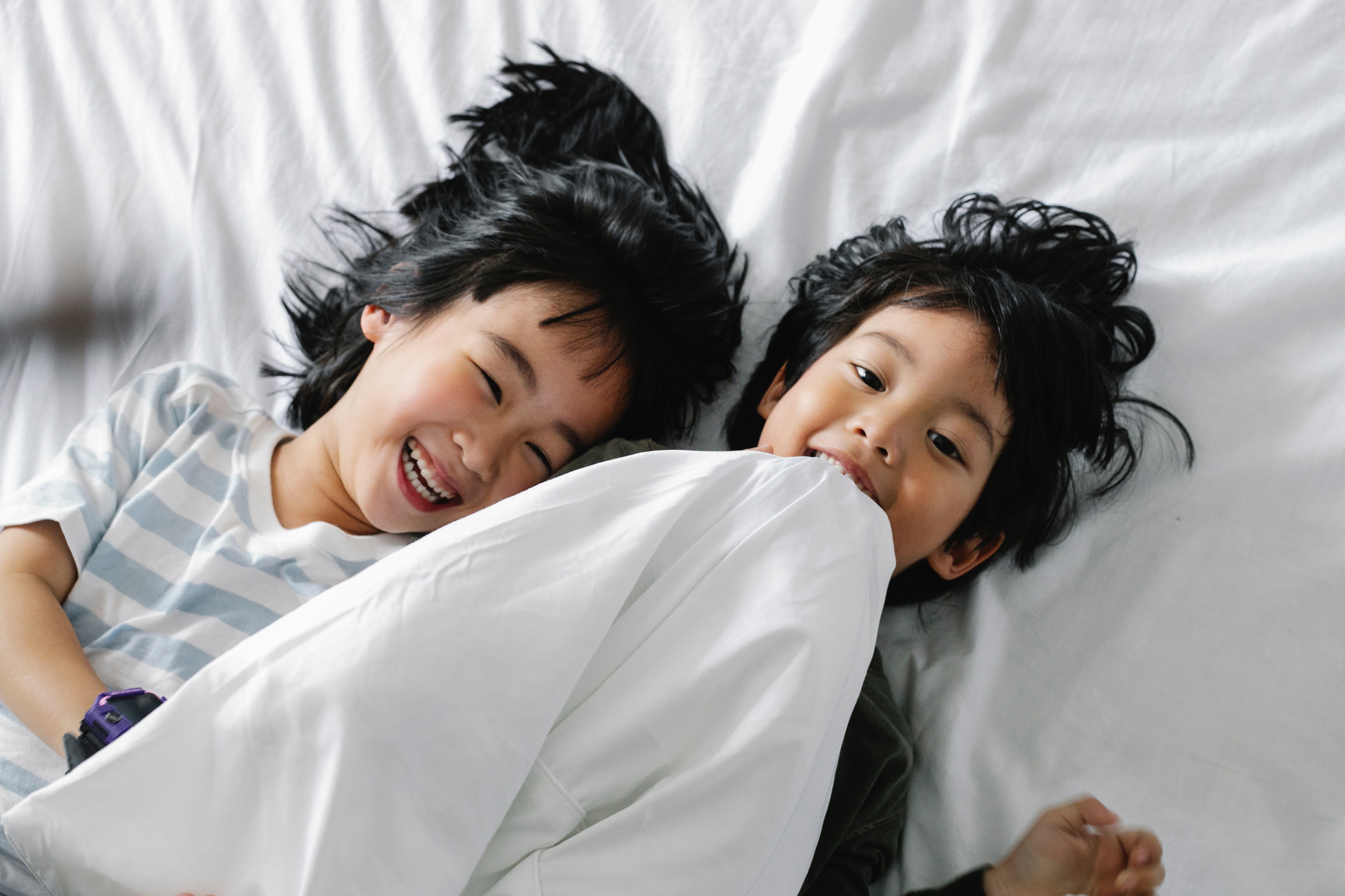 Two children laying in bed and laughing