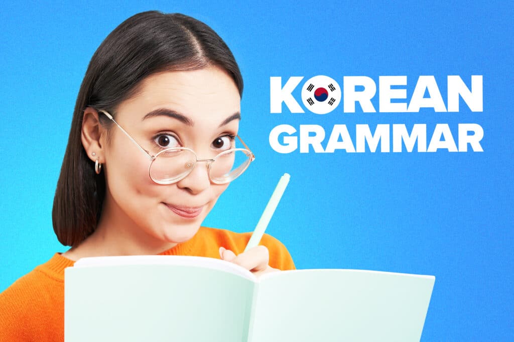 Woman in orange shirt and glasses holding notebook and pen, next to text reading "Korean Grammar"