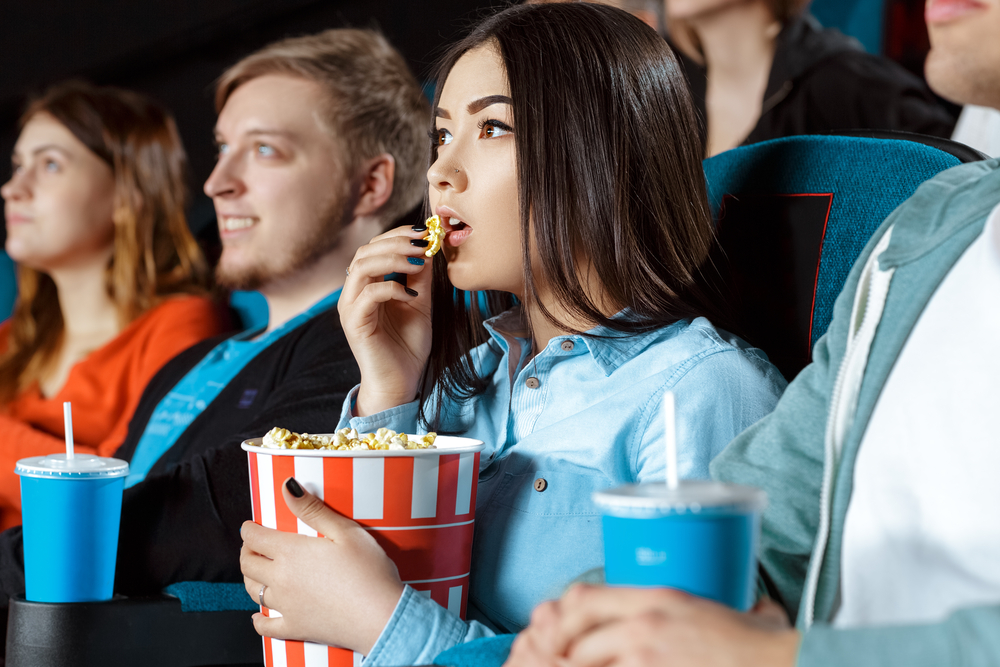 girl eating popcorn while watching a portuguese movie