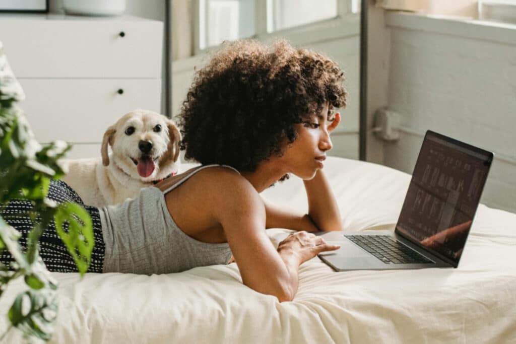 Woman watching laptop next to dog
