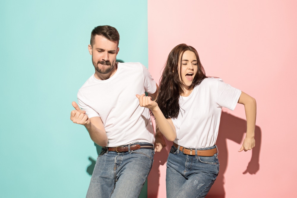 a-young-man-and-young-woman-dancing-funnily-in-front-of-blue-and-pink-trendy-color-background