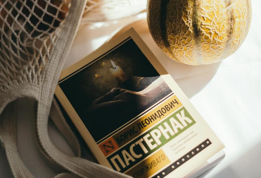 A Russian book on a table with a beach bag and a melon