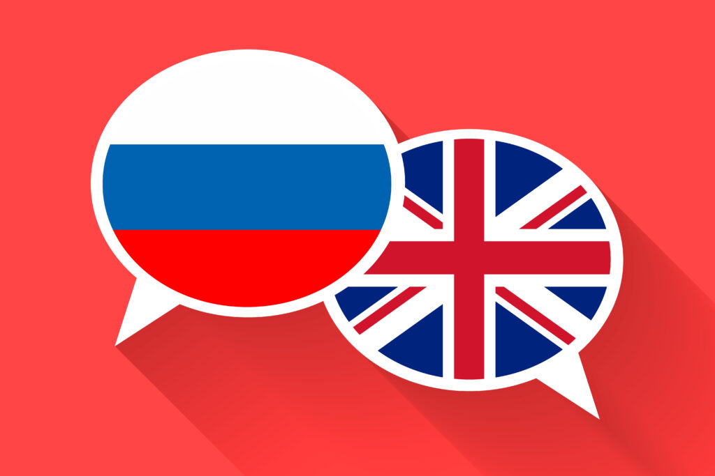 two speech bubbles with the russian flag and british flag against a red background