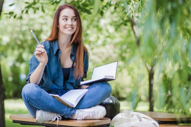 redhaired woman sitting outside with a notebook and pen