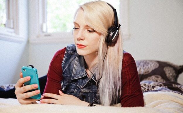 blonde woman with headphones on her phone