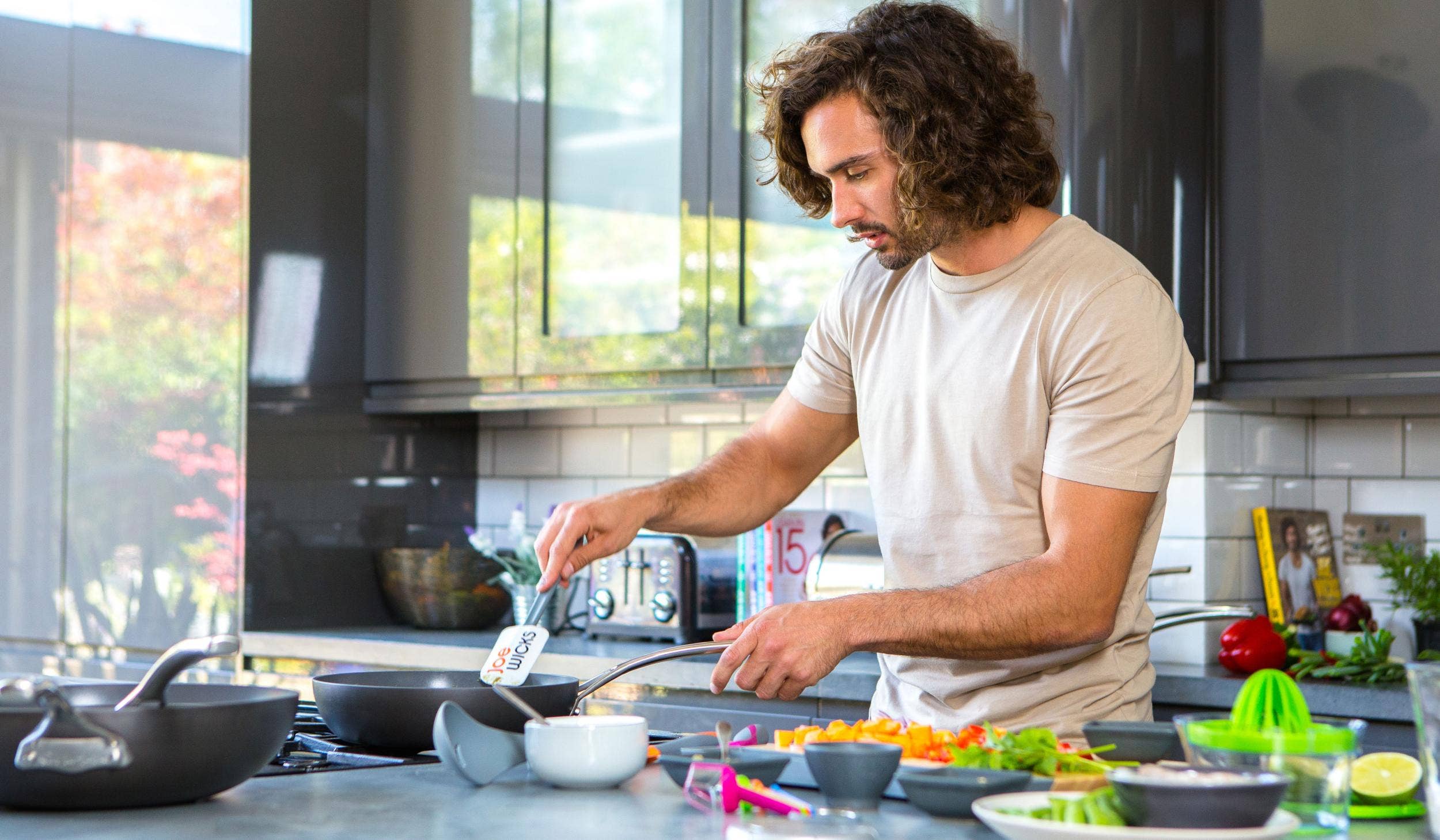 long haired man cooking vegetables in the kitchen