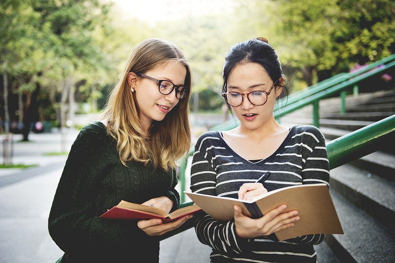two women walking and studying books together