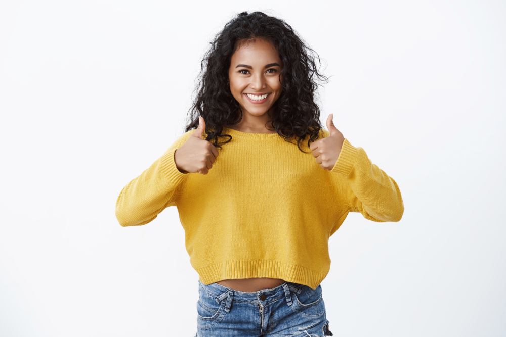 girl in a yellow sweater giving thumbs up