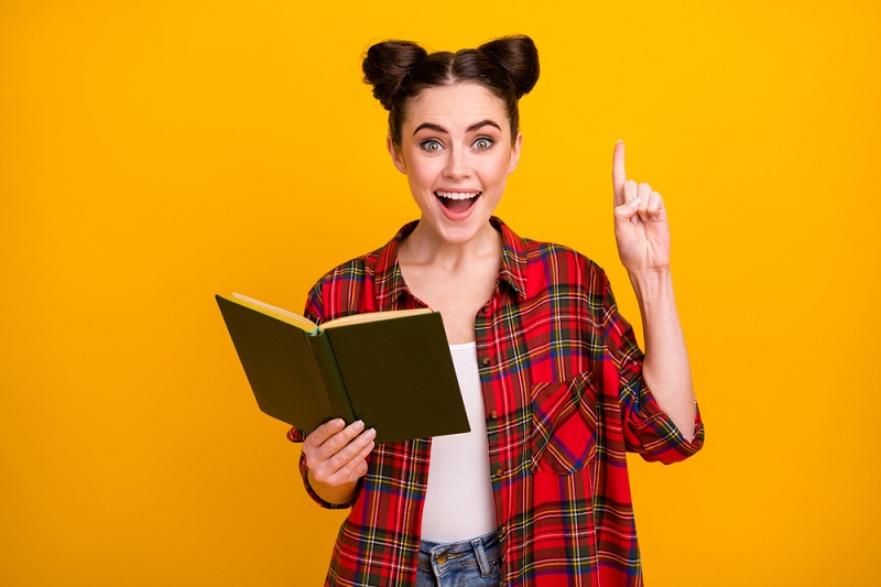 happy woman reading a book with a yellow background