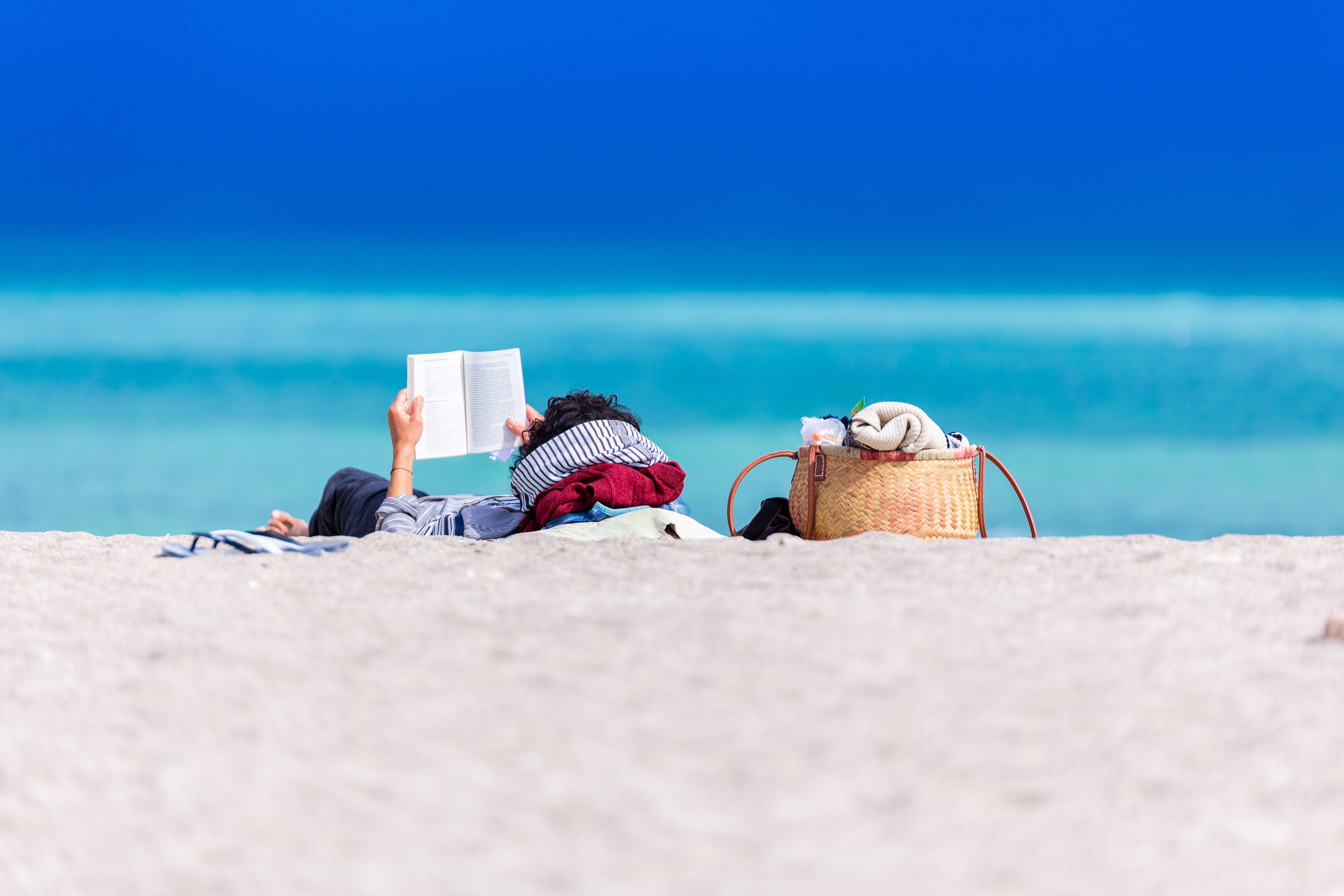 man lying on the beach reading a book