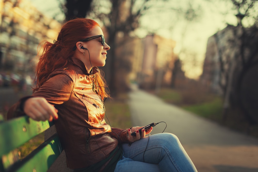 woman sitting on bench listening to music on headphones
