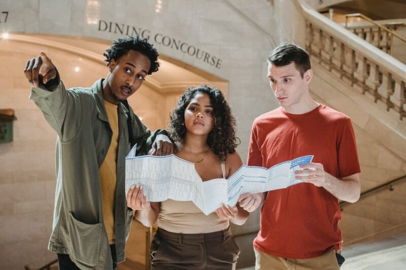 Three young multiethnic people consulting a map, giving directions