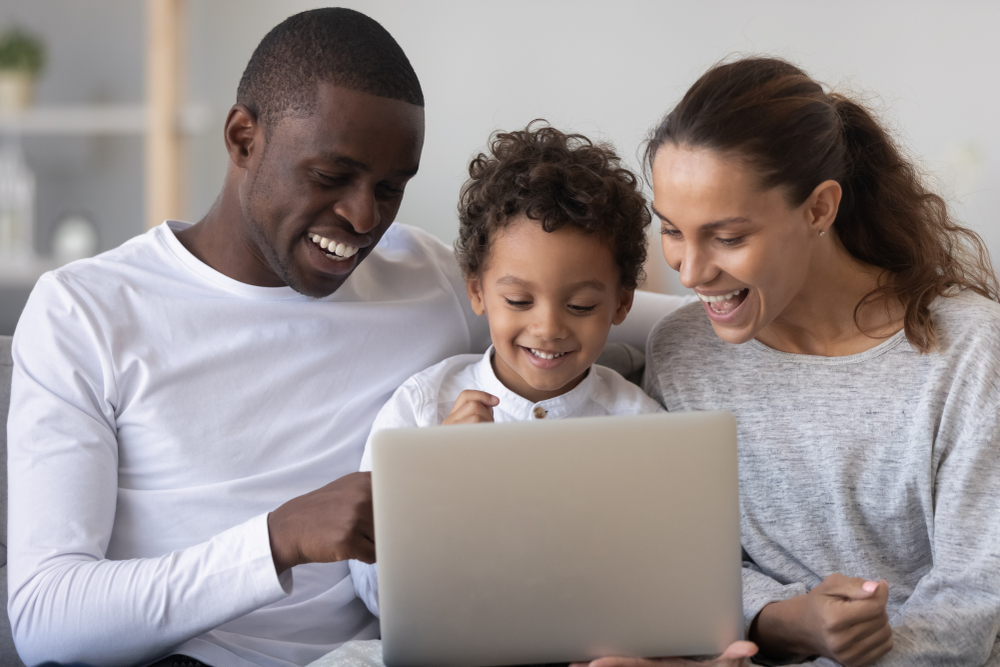 mom dad and son using laptop to learn spanish as a family at home