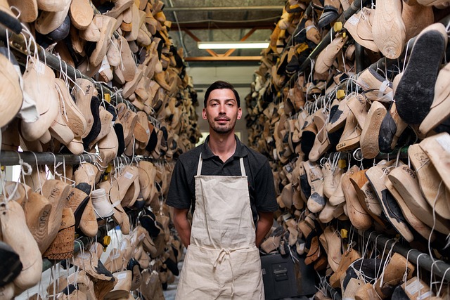 Shoemaker standing between racks of shoes and shoe forms
