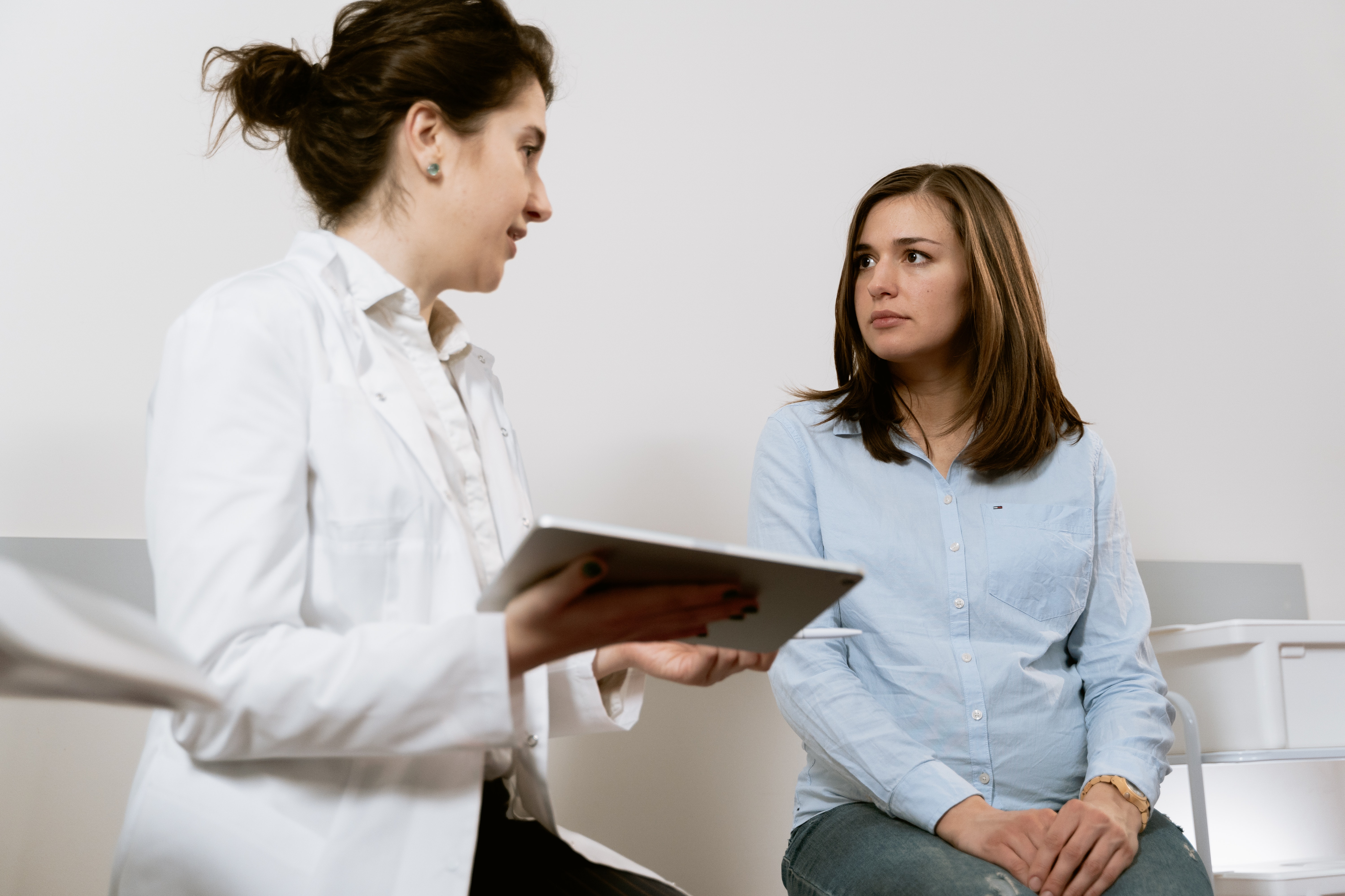 a-doctor-holding-an-ipad-talking-to-a-female-patient