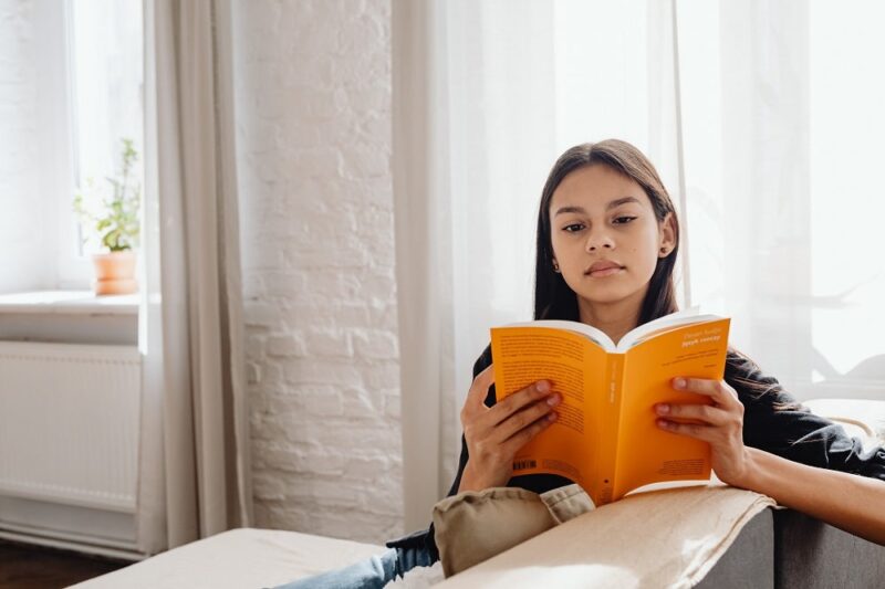 young-woman-reading-a-book-with-windows-in-the-background