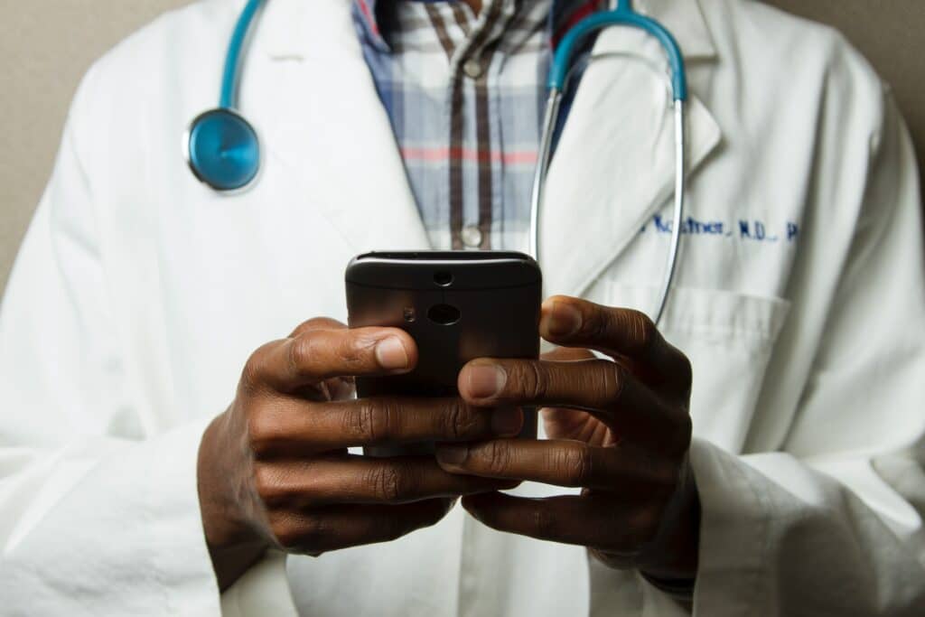 doctor in white coat consulting his phone