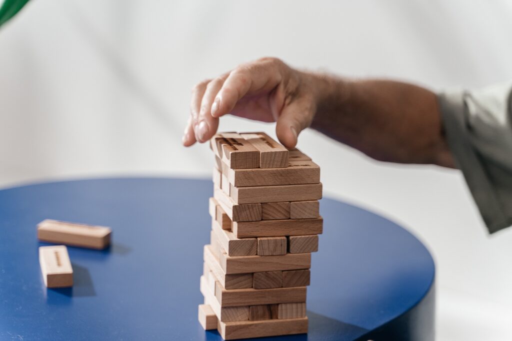 man's-hand-stacking-jenga-blocks-on-round-blue-table