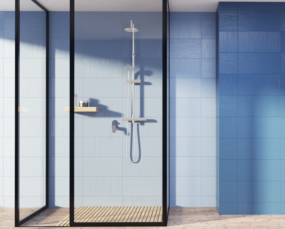 Blue-bathroom-interior-with-a-wooden-floor-a-shower-stall-with-glass-walls-and-an-empty-wall-fragment