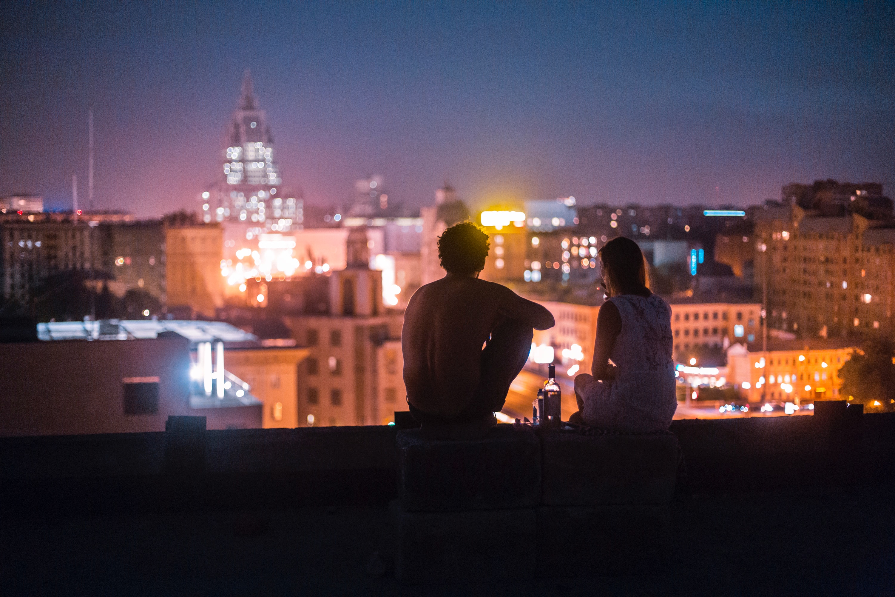 Couple sitting on top of a building at night