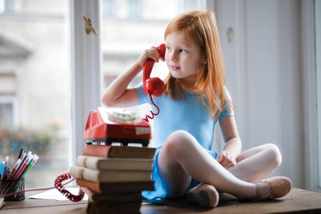 little-girl-holding-red-telephone-receiver-to-ear