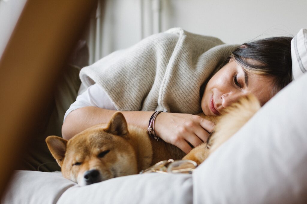 A woman sleeping next to her dog.