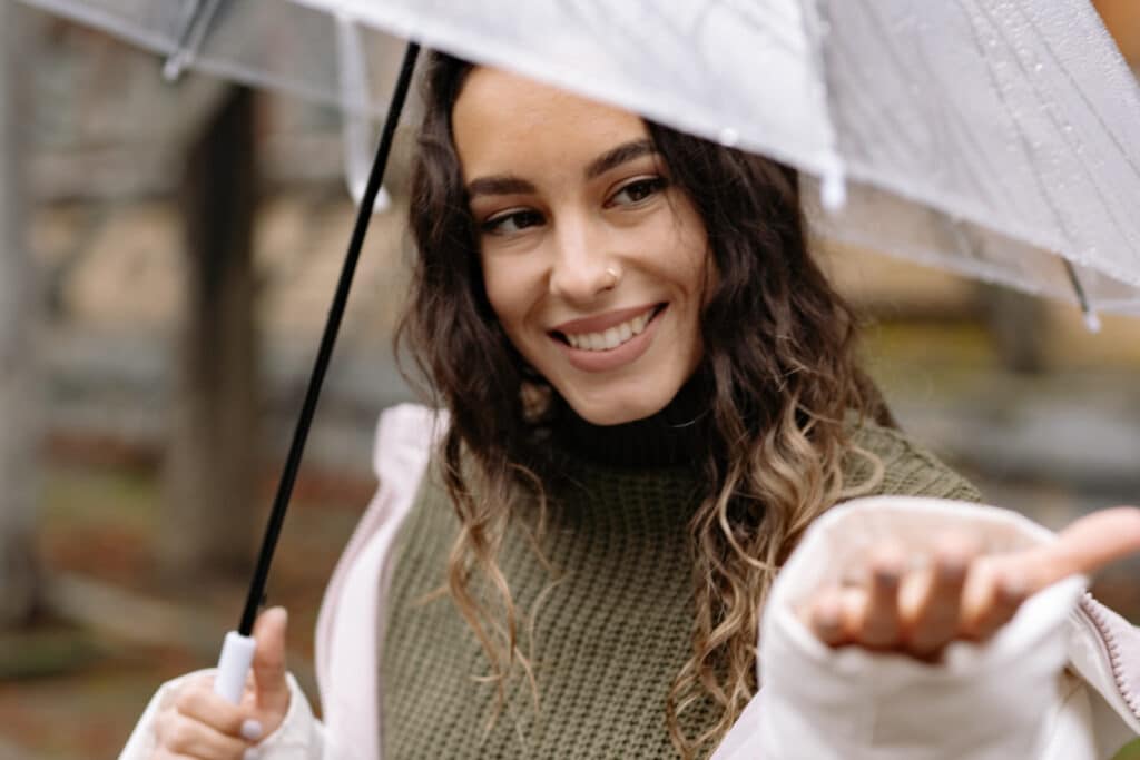 Woman stands in the rain under an umbrella