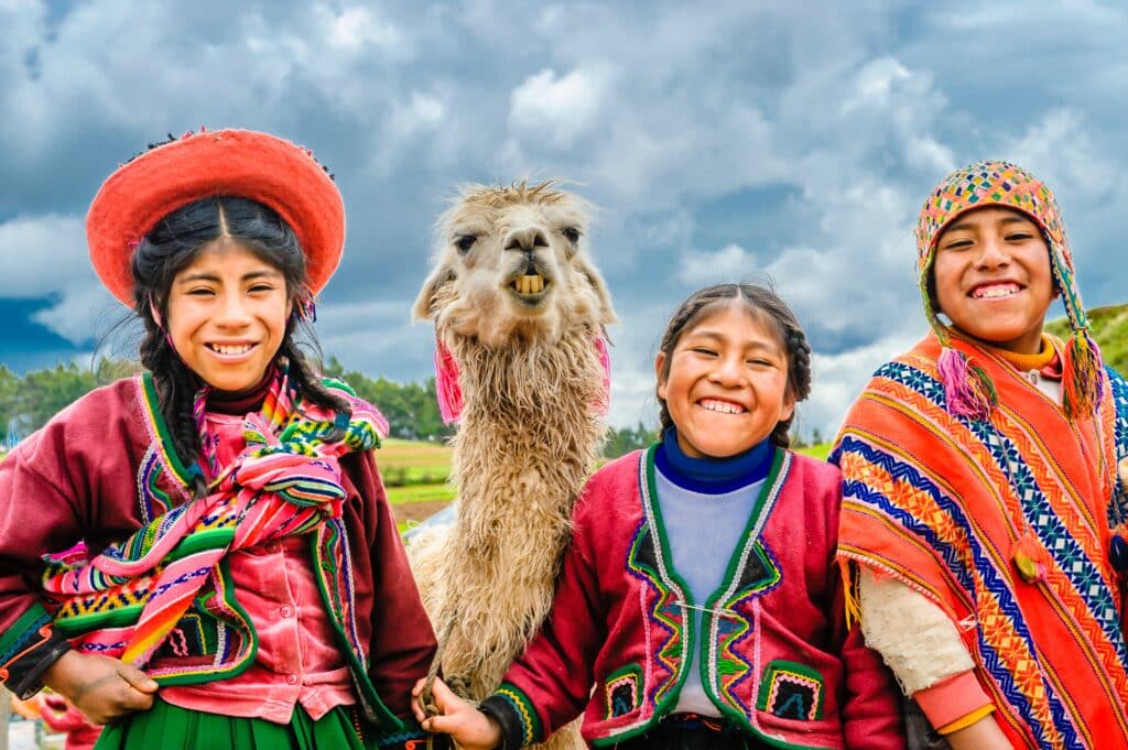 Latin Americans in traditional dress posing with a llama