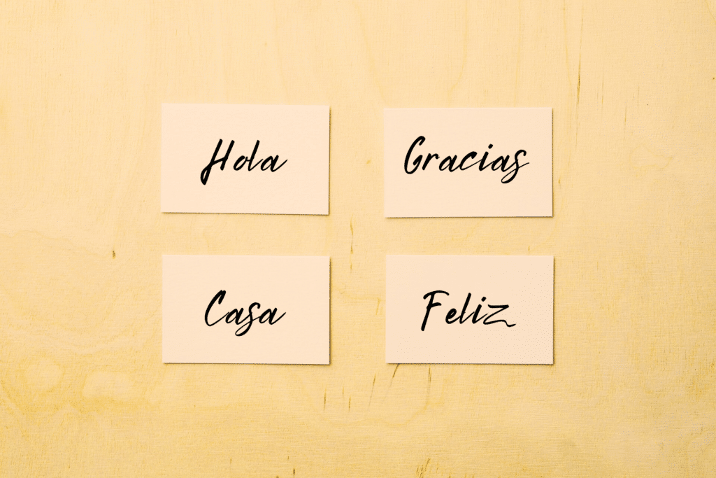 four-beige-flashcards-against-bright-yellow-background-with-the-spanish-words-hola-gracias-casa-and-feliz