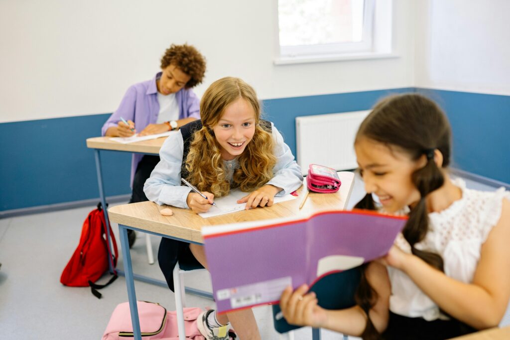 picture-of-a-student-showing-her-notebook-to-the-student-sitting-behind-smiling