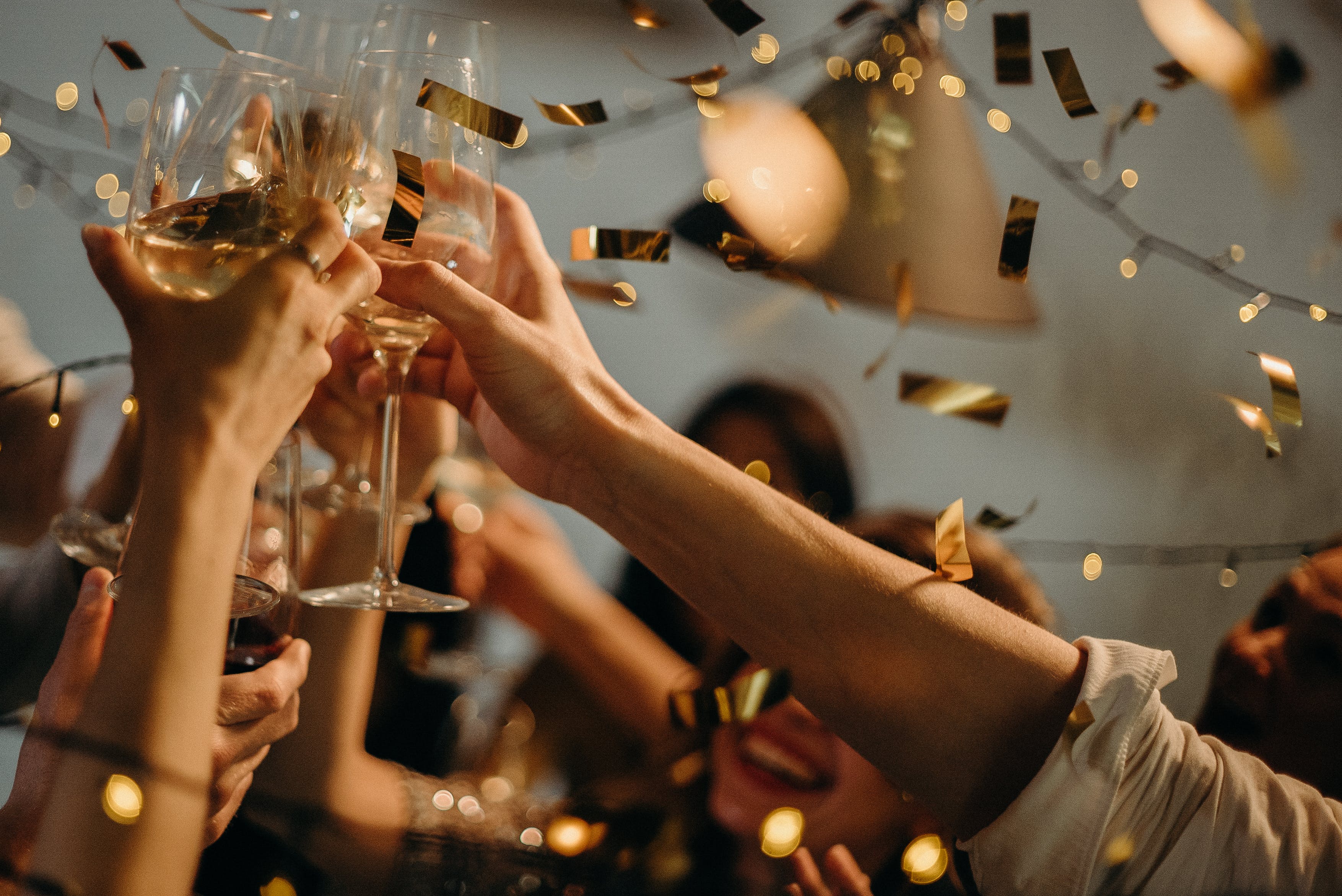 close-up-photo-of-people-toasting-wine-glasses-surrounded-by-gold-confetti