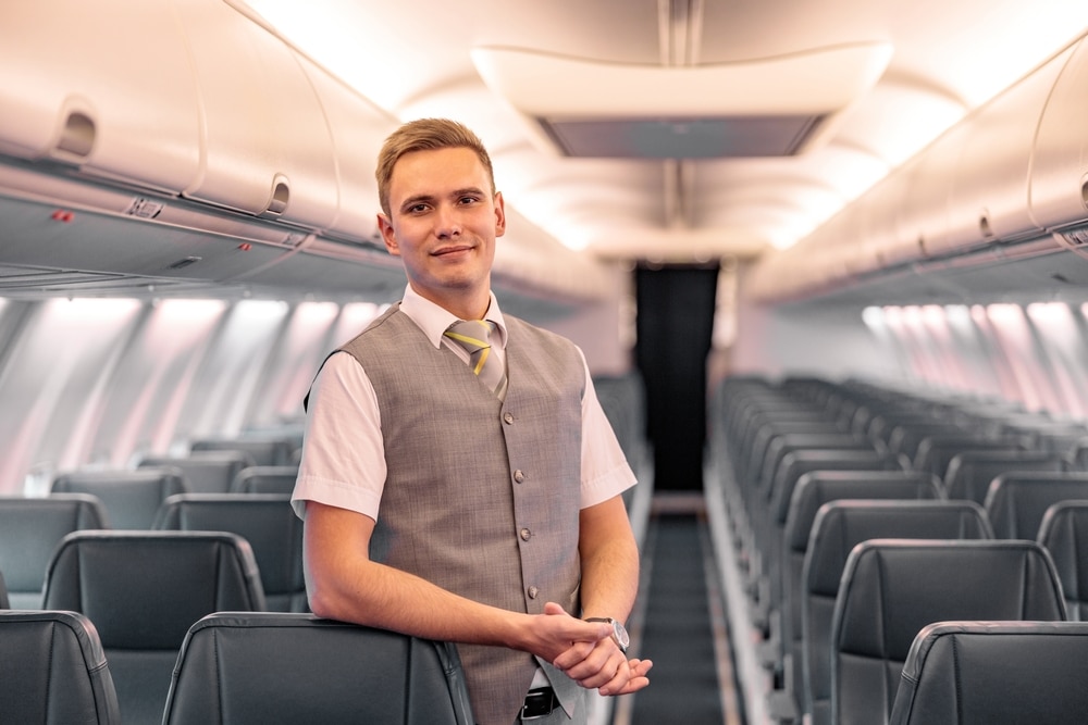 Male-Flight-Attendant-Standing-in-Aircraft-Aisle