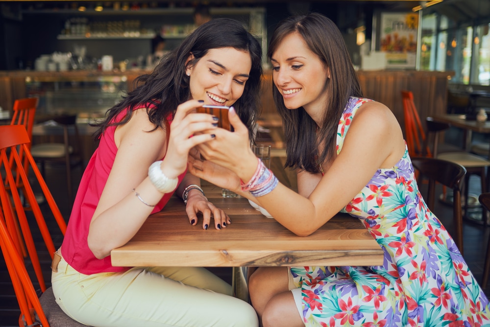 two-young-women-looking-at-one-phone