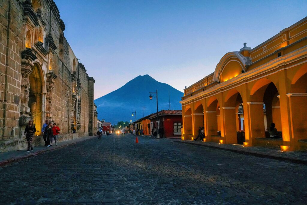 A view down a street in Antigua, Guatemala with a volcano looming in the background