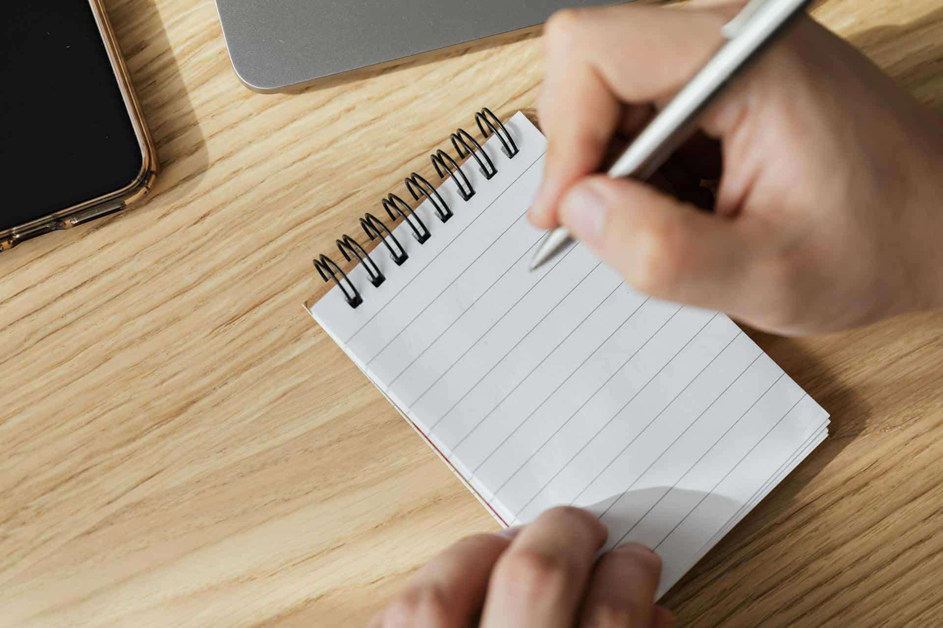 hand-with-white-pen-writing-on-blank-notepad