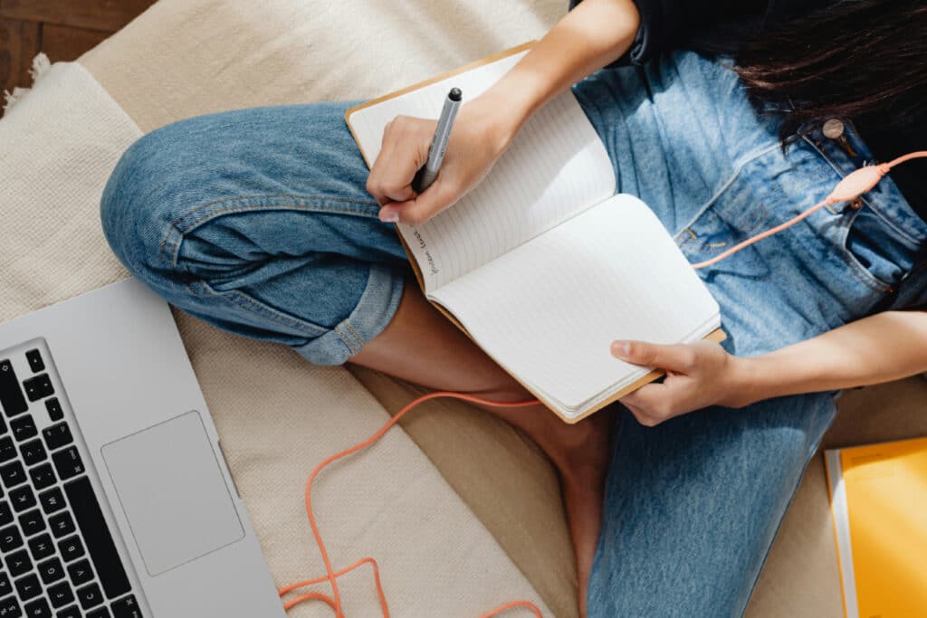 Person in jeans writing in a notebook